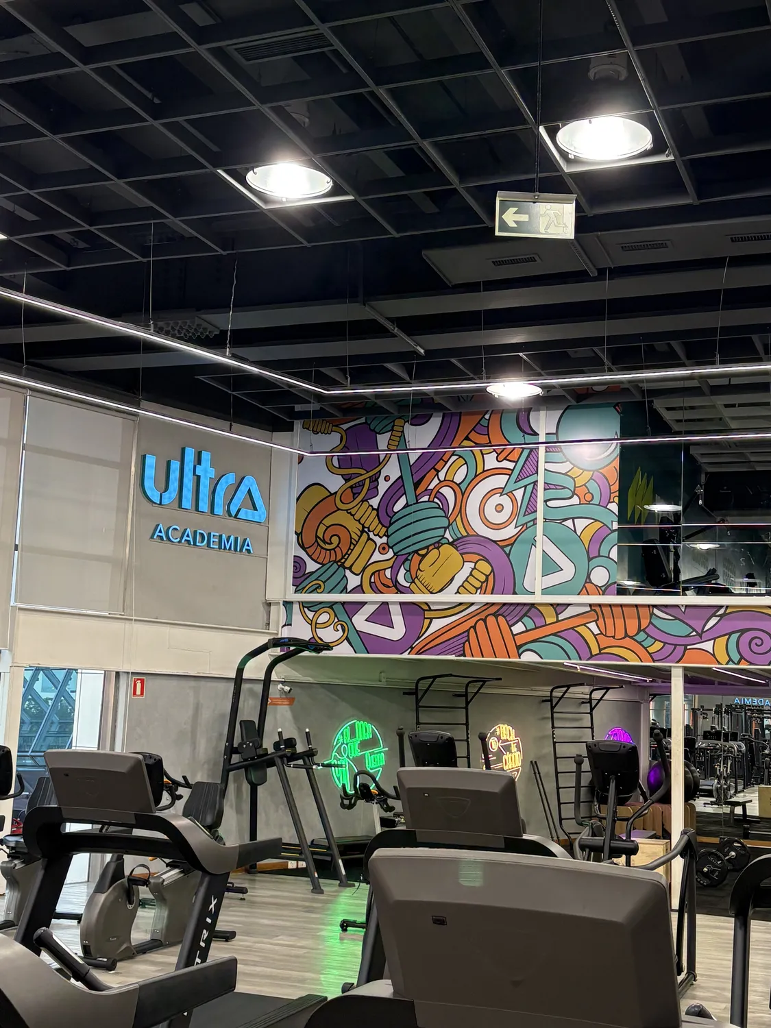 Reforma Ultra Academia: recepção com mural colorido e a marca da academia na parede